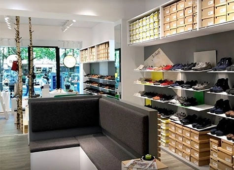 Innenansicht einer modernen Schuhboutique mit Regalen voller verschiedenfarbiger Schuhe und einer Sitzecke
