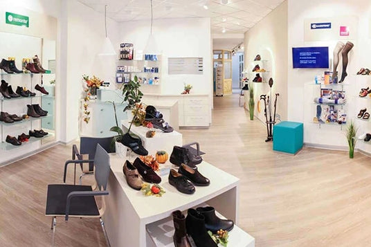 Innenansicht einer modernen Schuhboutique mit verschiedenen Schuhen auf Regalen und Tischen